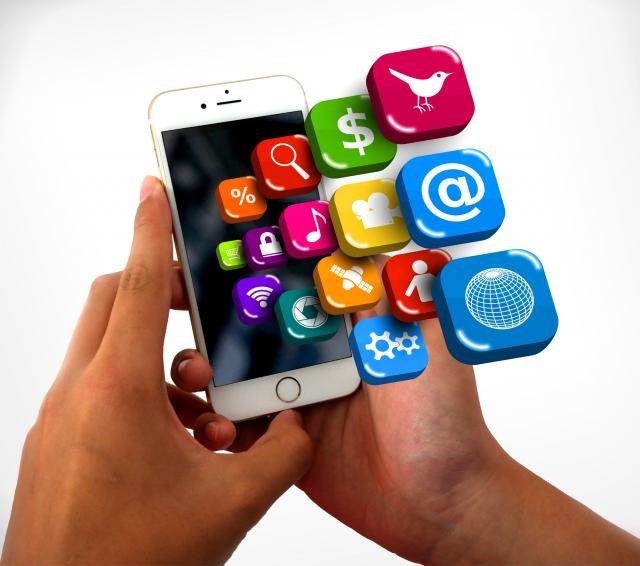 mãos seguram um celular, com ícones de diversos aplicativos.